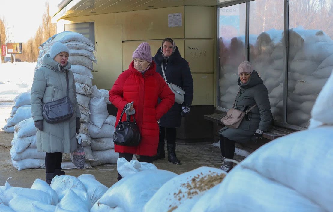 Mujeres esperan en una parada de autobús protegida por sacos de arena tras el reciente bombardeo ucraniano en Belgorod, Rusia, el 12 de enero de 2024.