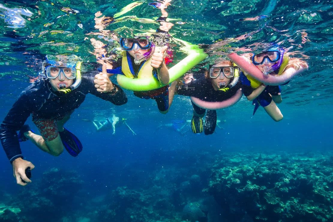 La familia practica snorkel en la Gran Barrera de Coral, Australia.