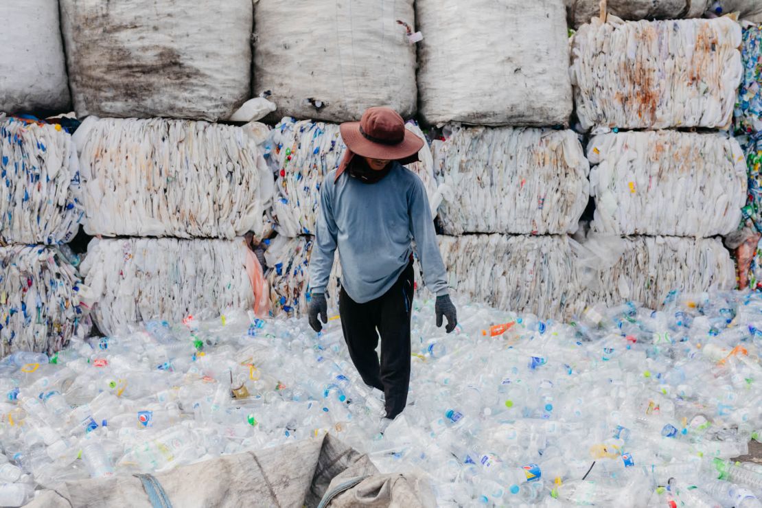 Un hombre trabaja entre una pila de botellas de plástico preparadas para reciclar en uno de los centros de reciclaje informales de Bangkok.