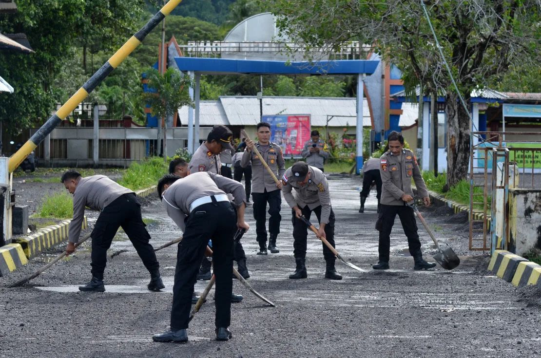 Agentes de policía barren material volcánico acumulado en el suelo, tras las erupciones del volcán monte Ruang en Célebes Septentrional, Indonesia, el 19 de abril de 2024.