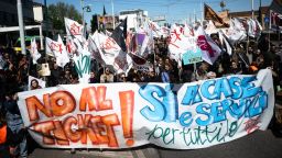 Los manifestantes sostienen un cartel que dice "No a las multas, sí a las casas y servicios para todos" mientras participan en una manifestación contra la nueva tarifa. Crédito: Marco Bertorello/AFP/Getty Images.