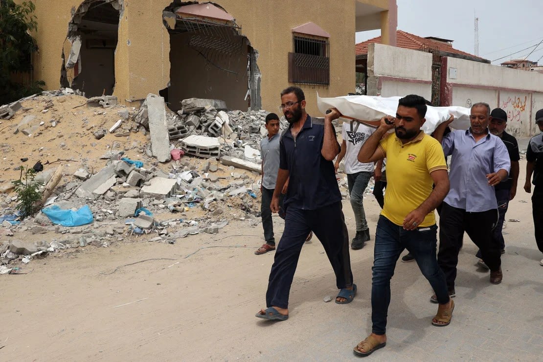 Personas trasladan un cuerpo después de identificarlo entre los cadáveres desenterrados de una fosa común encontrada en el Complejo Médico Nasser en el sur de Gaza. Crédito: AFP/Getty Images