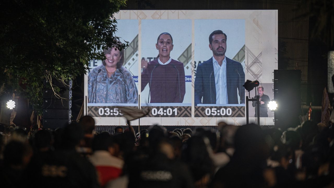 People watch on a huge screen (L to R) Mexico's presidential candidates Xochitl Galvez of the Fuerza y Corazon por Mexico coalition party, Claudia Sheinbaum of the Morena party, and Jorge Alvarez Maynez of the Citizens' Movement party during the second presidential debate ahead of the June 2 national election as  in Mexico City, on April 28, 2024. (Photo by CARL DE SOUZA / AFP)