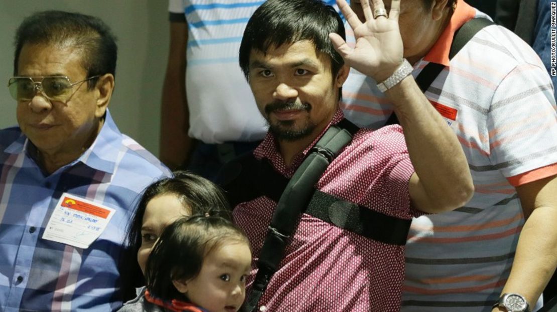 Pacquiao saluda a la multitud al llegar, junto con su esposa Jinkee y su hijo menor Israel (al fondo a la izquierda) el 13 de mayo en el aeropuerto de Filipinas.