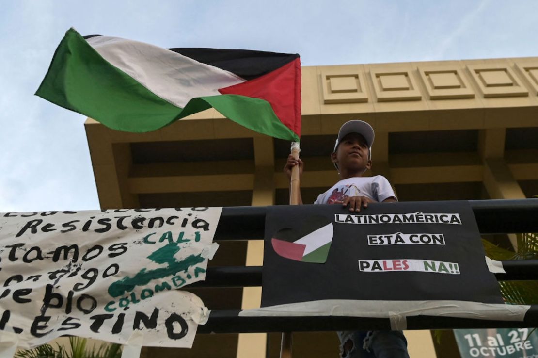 Un niño sostiene una bandera de Palestina junto a un cartel en el que se lee "América Latina está con Palestina" durante una manifestación de apoyo a los palestinos en Cali, Colombia, el 19 de octubre de 2023, en medio de los ataques aéreos israelíes contra Gaza en represalia por un ataque sorpresa de Hamas el 7 de octubre de 2023.