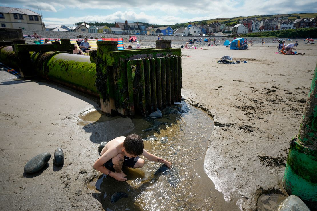 Los desbordamientos por tormentas son habituales en las playas del Reino Unido. En la imagen, un niño juega con el vertido de un desbordamiento en la playa de Borth, Gales.