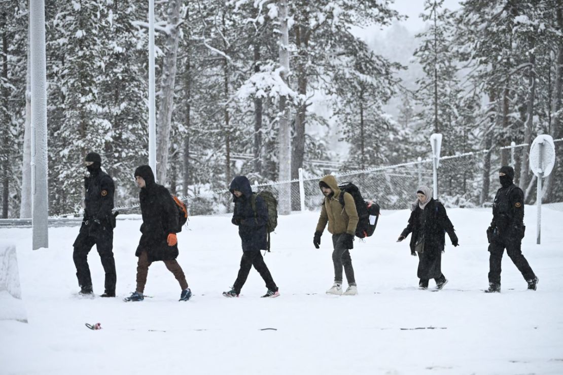 Agentes de la guardia fronteriza finlandesa escoltan a los migrantes a su llegada a la estación fronteriza de Raja-Jooseppi con Rusia en Inari, norte de Finlandia, el 25 de noviembre de 2023.