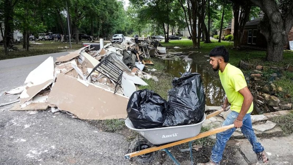 Un trabajador de la construcción mueve bolsas de basura llenas de artículos dañados por las inundaciones a una pila de escombros mientras limpia los daños causados por las inundaciones en el barrio de River Plantation el lunes 6 de mayo de 2024 en Conroe, Texas.