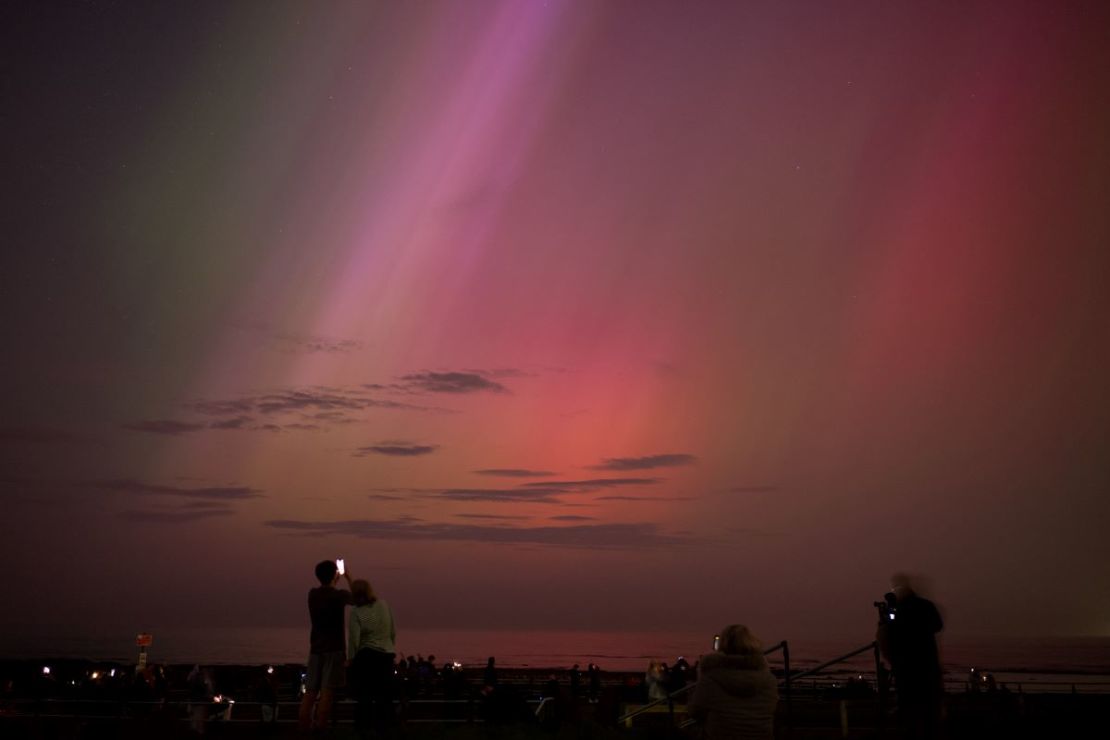 La gente visita el faro de St Mary en Whitley Bay para ver la aurora boreal el 10 de mayo de 2024 en Whitley Bay, Inglaterra.