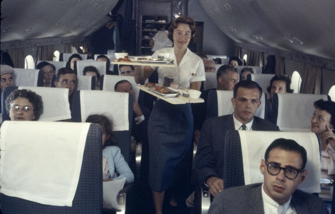 Una azafata de Pan American Airline sirve bandejas de comida a los pasajeros de un avión en 1958.