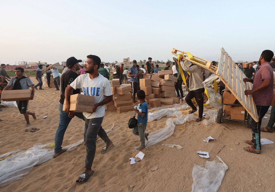 Los palestinos recogen paquetes de ayuda que fueron entregados a Gaza a través de un muelle construido por Estados Unidos, visto desde el centro de Gaza el 18 de mayo. Crédito: Ramadan Abed/Reuters.