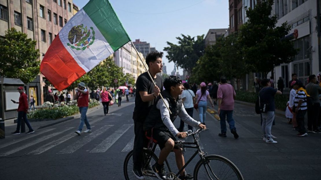 Jóvenes con una bandera mexicana mientras simpatizantes de la candidata presidencial opositora Xochitl Gálvez, del partido de coalición Fuerza y Corazón por México, marchan hacia la Plaza del Zócalo el 19 de mayo de 2024.