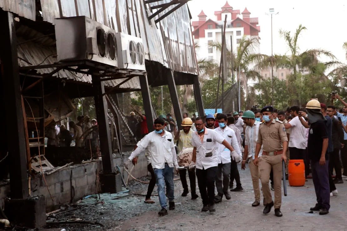 Los rescatistas llevan el cuerpo de una persona que murió en el incendio en la sala de juegos de Rajkot, India, el 25 de mayo. (Foto: Chirag Chotaliya/AP).