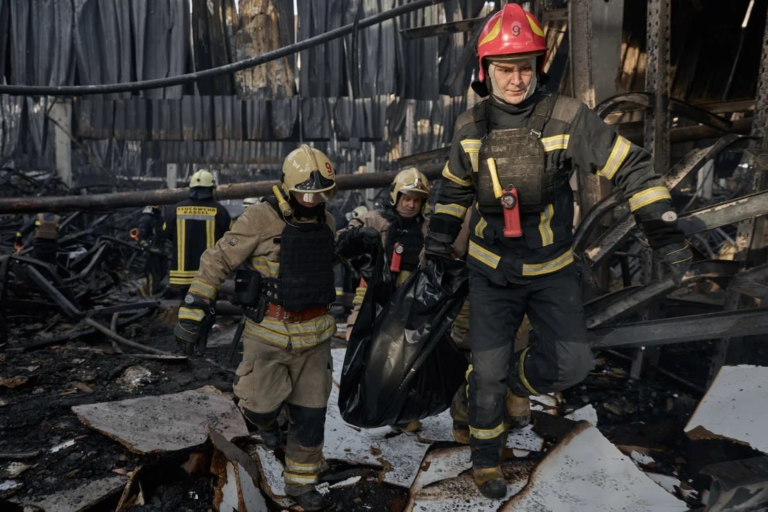 Los trabajadores de emergencia sacan el cuerpo de una víctima de un ataque ruso que afectó a un gran almacén en Járkiv.