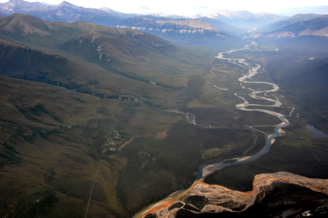 Una vista aérea del río Kutuk en el Parque Nacional Puertas del Ártico de Alaska que parecepintura naranja derramándose en el agua azul clara.