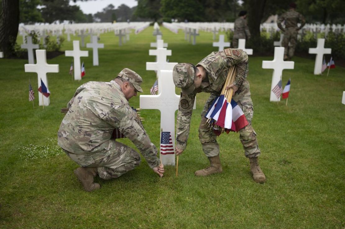 Militares estadounidenses colocan banderas estadounidenses y francesas junto a las tumbas de los soldados caídos en el Cementerio Estadounidense de Normandía el 5 de junio de 2023 en Colleville-sur-Mer, Francia. Crédito: Christopher Furlong/Getty Images