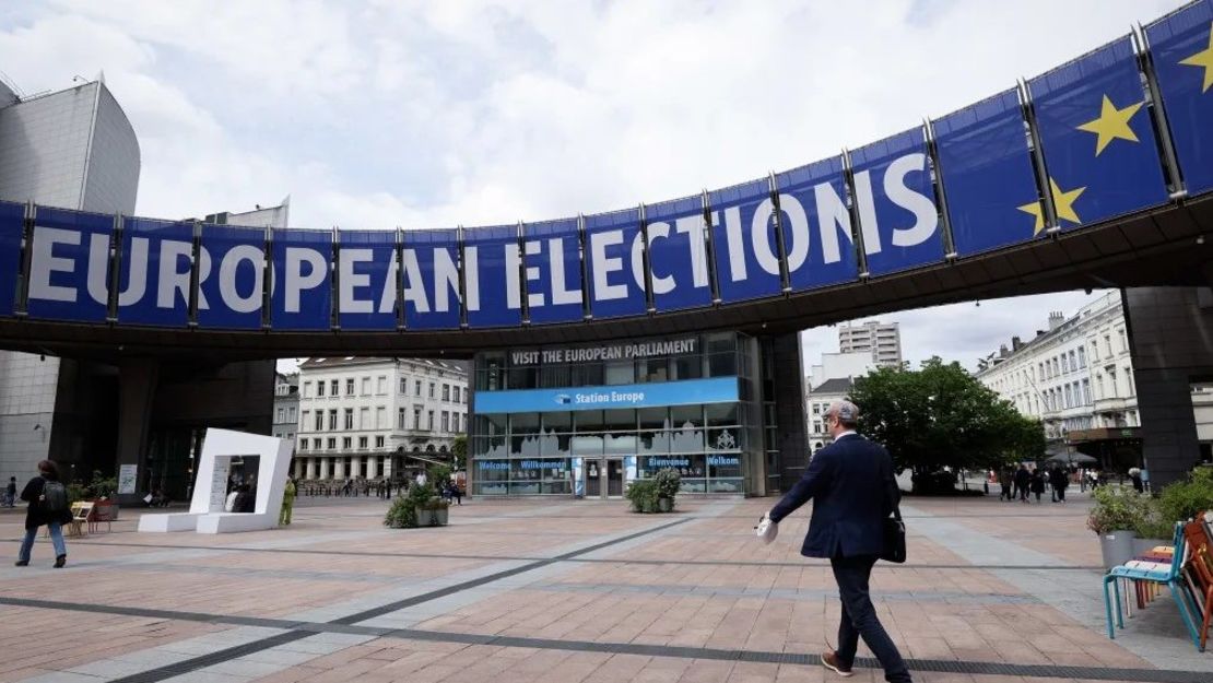 Unos peatones pasan junto a una pancarta desplegada en el edificio del Parlamento Europeo en Bruselas el 17 de mayo de 2024.