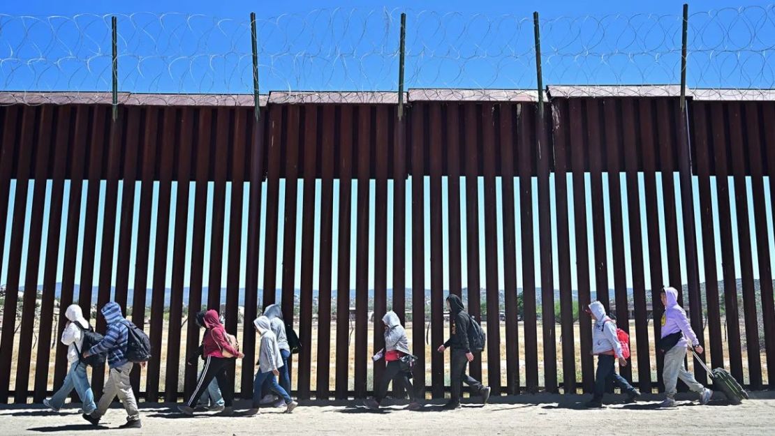 Migrantes caminan por el lado estadounidense del muro fronterizo en Jacumba Hot Springs, California, el 5 de junio, después de cruzar desde México. (Foto: Frederic J. Brown/AFP/Getty Images).