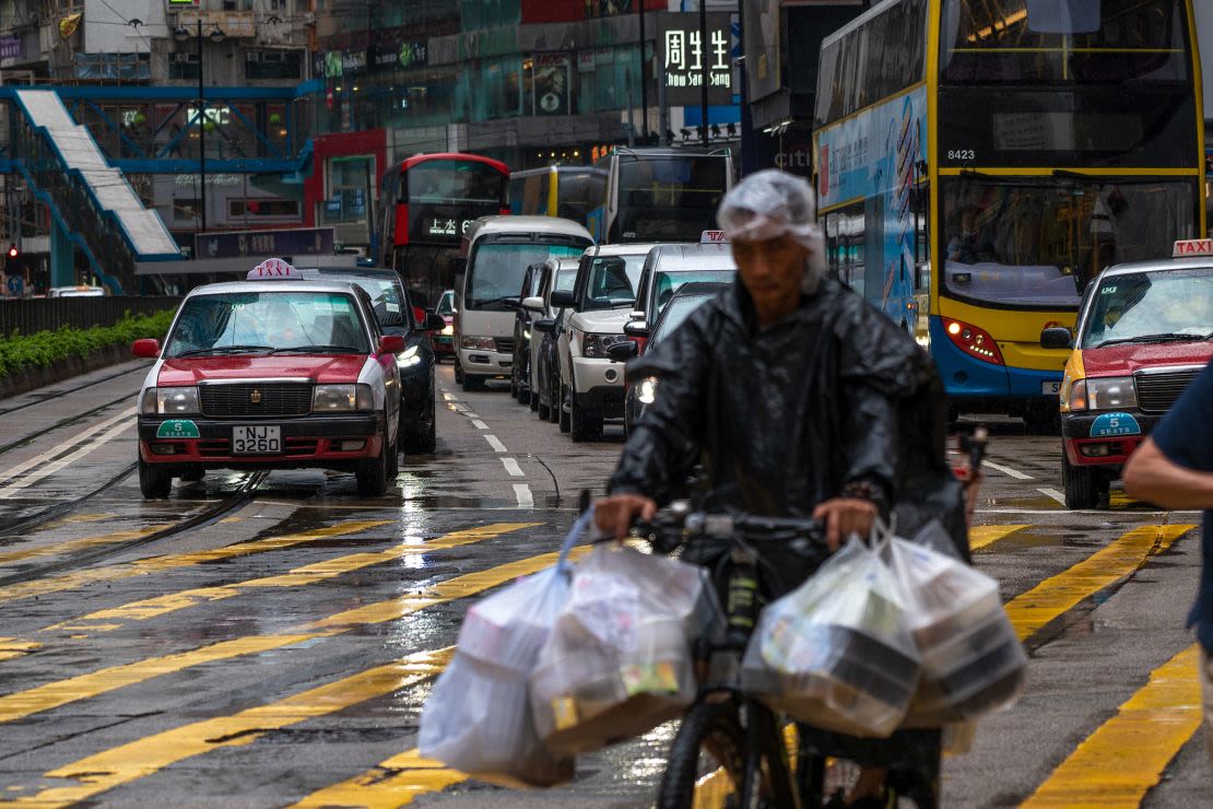 Un repartidor pedalea por una calle mientras los coches esperan a que cambie un semáforo, en Hong Kong el 24 de mayo de 2024.