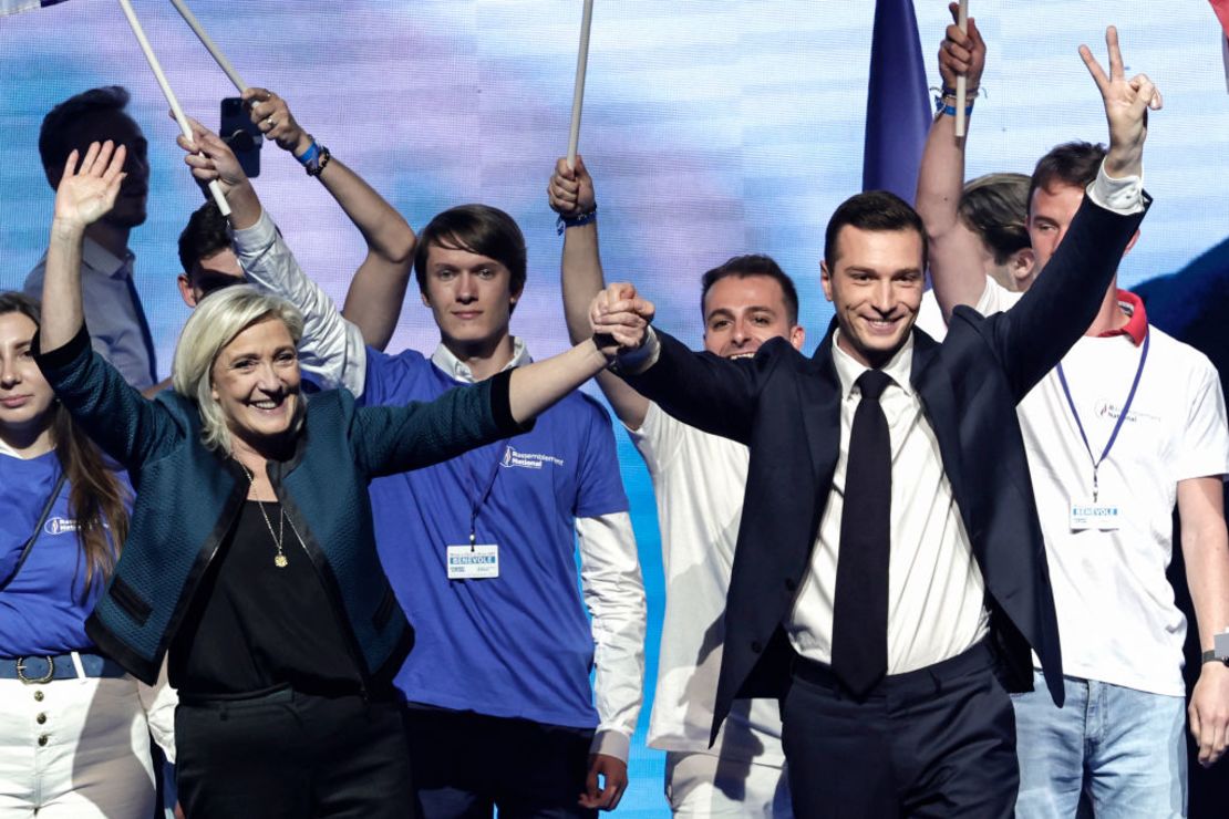 Jordan Bardella y Marine Le Pen, agitan sus manos en el escenario durante una actividad de campaña en París el 2 de junio de 2024.