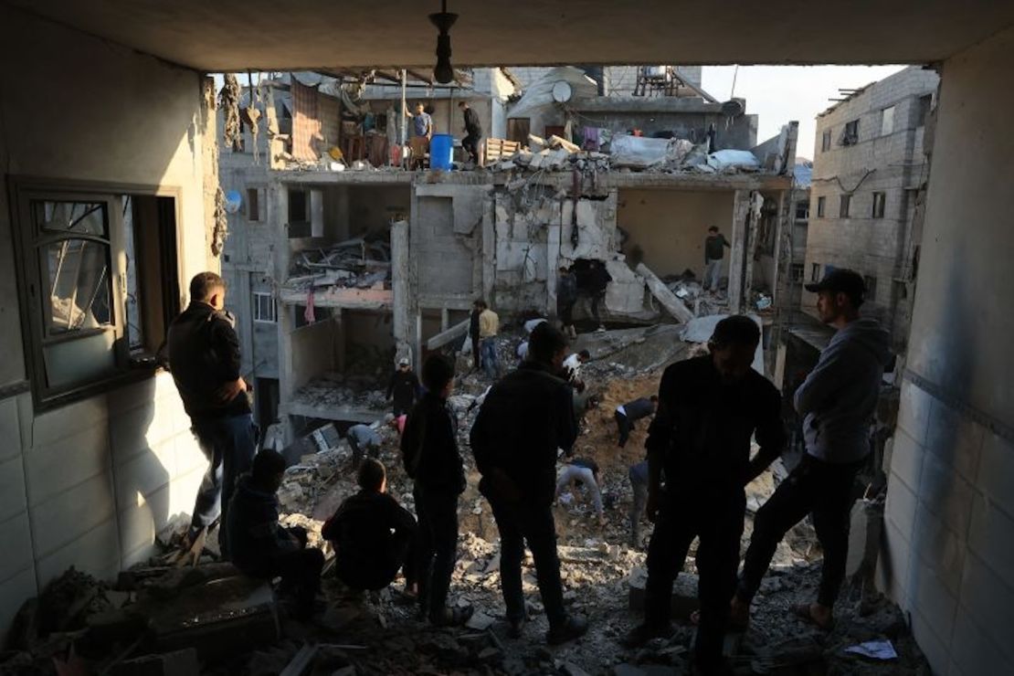 Palestinos inspeccionan la destrucción alrededor de edificios residenciales tras los ataques aéreos israelíes en el campo de refugiados de Rafah, en el sur de Gaza, el 1 de diciembre de 2023.