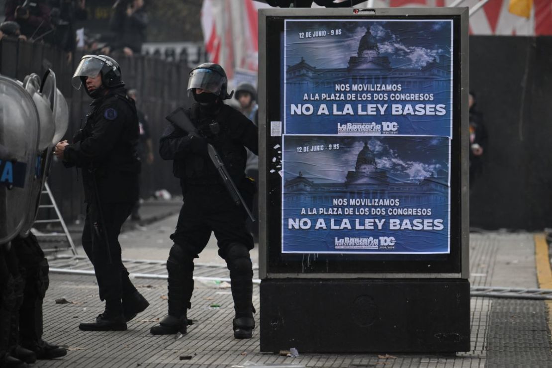 Oficiales de policía antidisturbios hacen guardia junto a señales contra las reformas del presidente Javier Milei cerca del Congreso Nacional en Buenos Aires el 12 de junio de 2024.