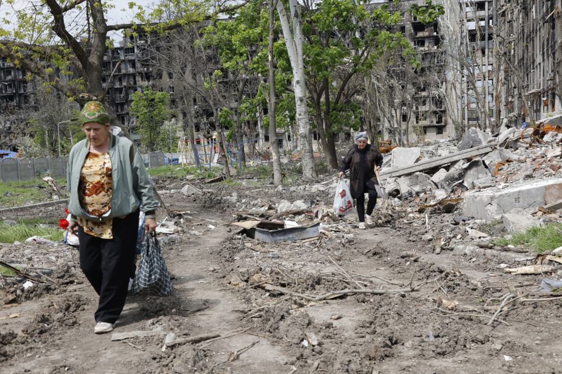 Unas mujeres pasan por delante de un edificio residencial destruido en Mariúpol en mayo de 2022. Crédito: Alexei Alexandrov/AP