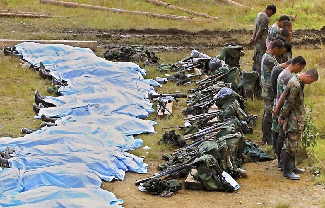 Paramilitares capturados de las Autodefensas Unidas de Colombia (AUC) se paran ante los cadáveres cubiertos de sus compañeros muertos en combates con el ejército nacional el 13 de junio de 2002 en Sonsón, Antioquia, al este de Medellín.