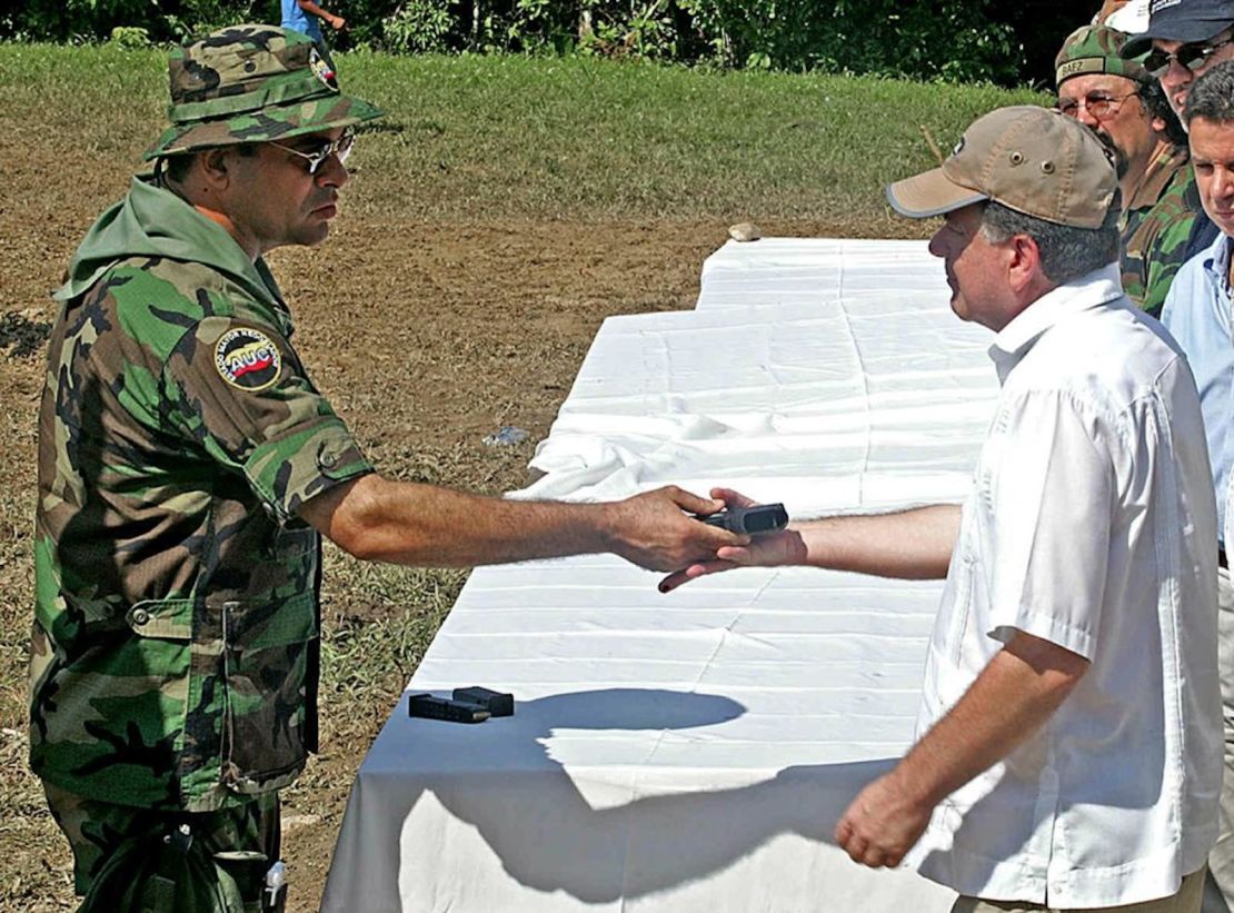 Salvatore Mancuso (izq.), líder de las derechistas Autodefensas Unidas de Colombia (AUC), entrega su arma al comisionado de paz del gobierno, Luis Carlos Restrepo, en el campamento base Campo Dos de Tibú, a 600 km al noreste de Bogotá, en el departamento de Norte de Santander, el 10 de diciembre de 2004. Unos 1500 combatientes del llamado Bloque Catatumbo se desmovilizaron en un polémico proceso de paz durante el gobierno del presidente Álvaro Uribe (2002-2010).