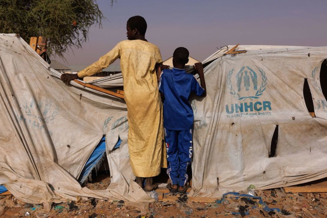 Dos niños miran por encima de una tienda de ayuda de ACNUR mientras refugiados recién llegados de Darfur (Sudán) se reúnen en un campo de reubicación cerca de la frontera el 19 de abril en Adre, Chad. Crédito: Dan Kitwood/Getty Images