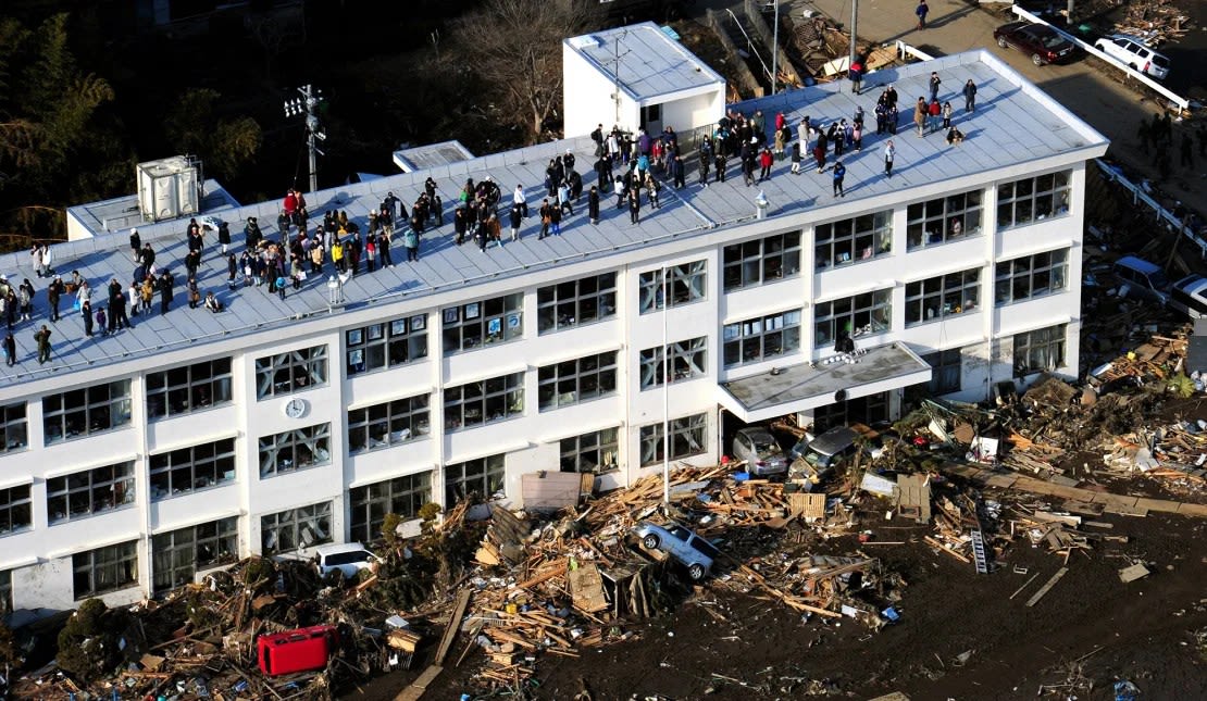 La gente evacua al techo de una escuela primaria después de que se anunciara una alerta de tsunami el 13 de marzo de 2011 en Higashimatsushima, Miyagi, Japón.