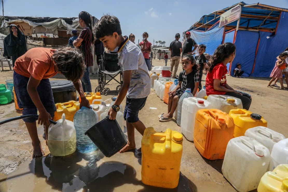Los palestinos hacen cola para recibir agua potable distribuida por organizaciones de ayuda en Deir al-Balah.