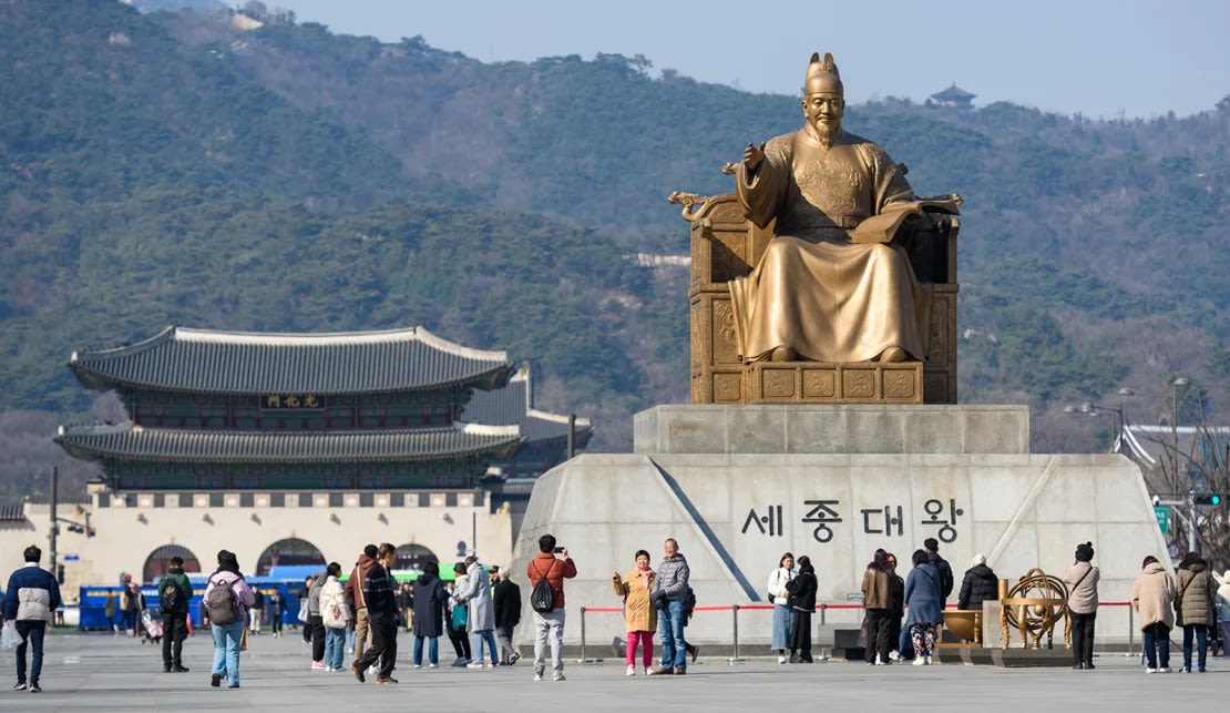 Los turistas visitan la estatua de Sejong el Grande de la dinastía Joseon en la plaza Gwanghwamun en Seúl, Corea del Sur, el 21 de febrero de 2024.