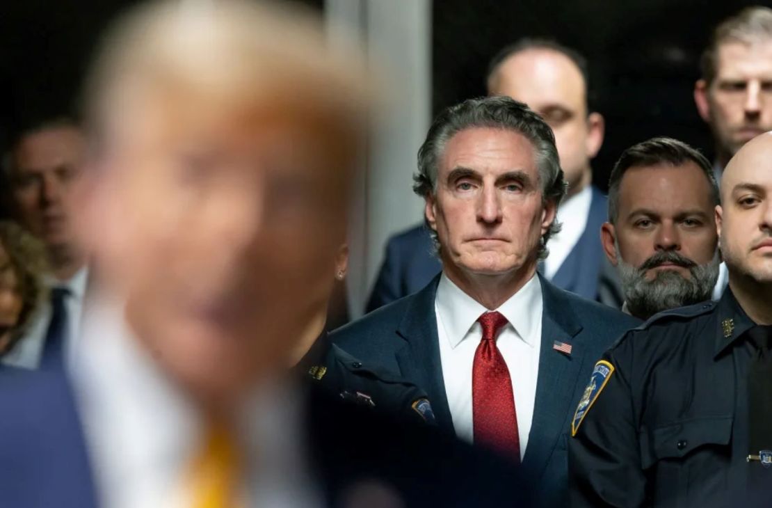 El gobernador de Dakota del Norte, Doug Burgum, escucha mientras Trump habla con los periodistas al final del día de procedimientos en el juicio penal de Trump por el dinero de su silencio en la ciudad de Nueva York el 14 de mayo de 2024.