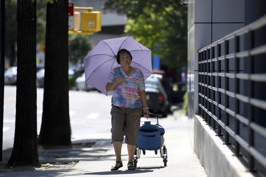 Una mujer usa un paraguas para protegerse del sol en el distrito de Queens de la ciudad de Nueva York, 18 de junio de 2024. La ciudad está bajo alerta de calor extremo. Crédito: Anthony Behar/SIPPL Sipa EE.UU./AP.