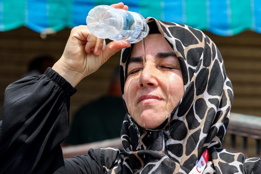 Una peregrina musulmana turca se vierte agua fría de una botella en la cabeza para refrescarse mientras espera en la ciudad santa de La Meca, en Arabia Saudita, el 20 de junio de 2024.