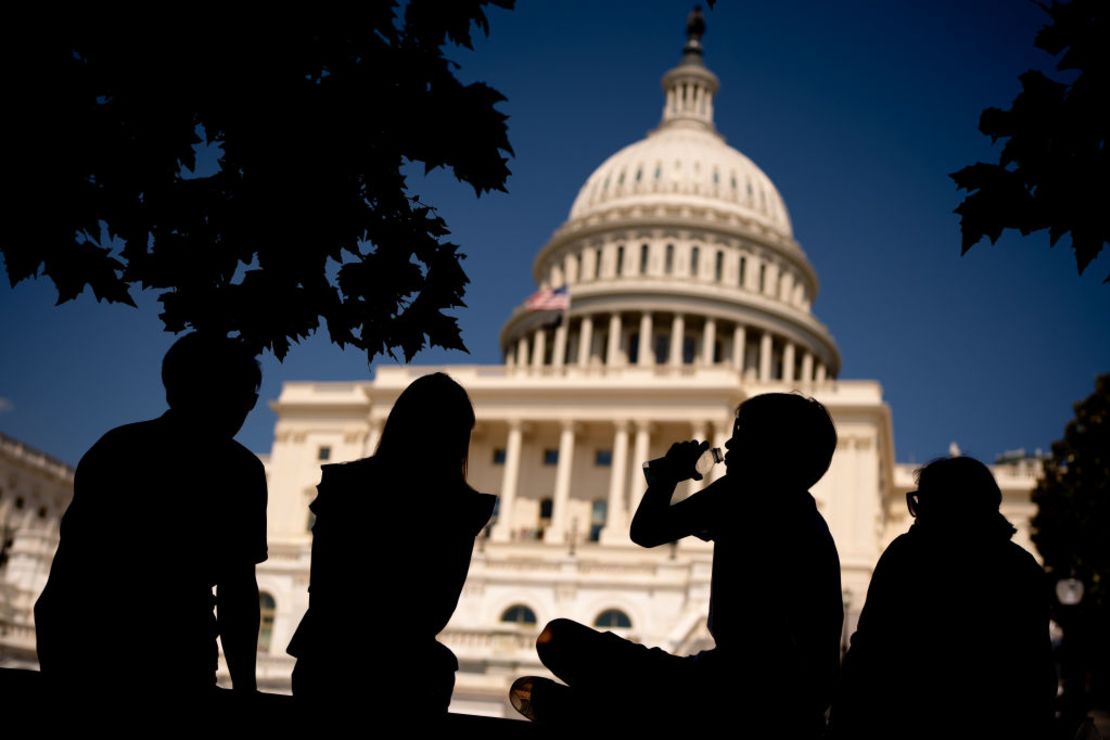 Jóvenes frente al Capitolio de EE.UU. toman un trago a la sombra mientras gran parte del noreste se prepara para una ola de calor el 21 de junio de 2024 en la ciudad de Washington.