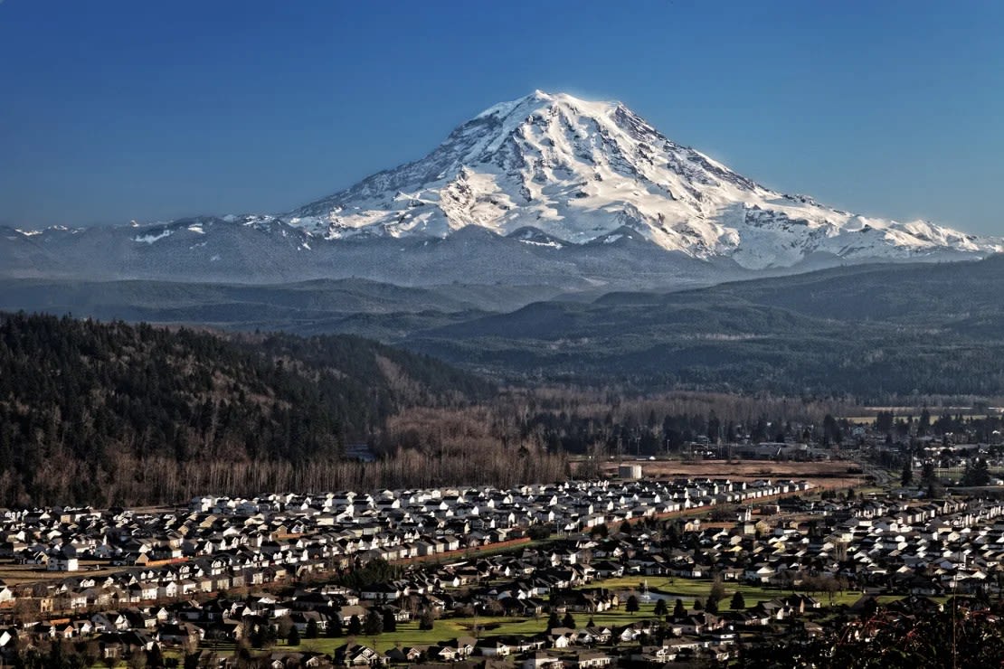 El monte Rainier, un volcán nevado, se cierne sobre el valle de Puyallup, cerca de Orting (Washington). La posibilidad de que se produzca un lahar -un flujo de escombros que se desplaza rápidamente provocado por el deshielo de la nieve y el hielo, típico de las erupciones volcánicas- supone una amenaza para las comunidades circundantes.