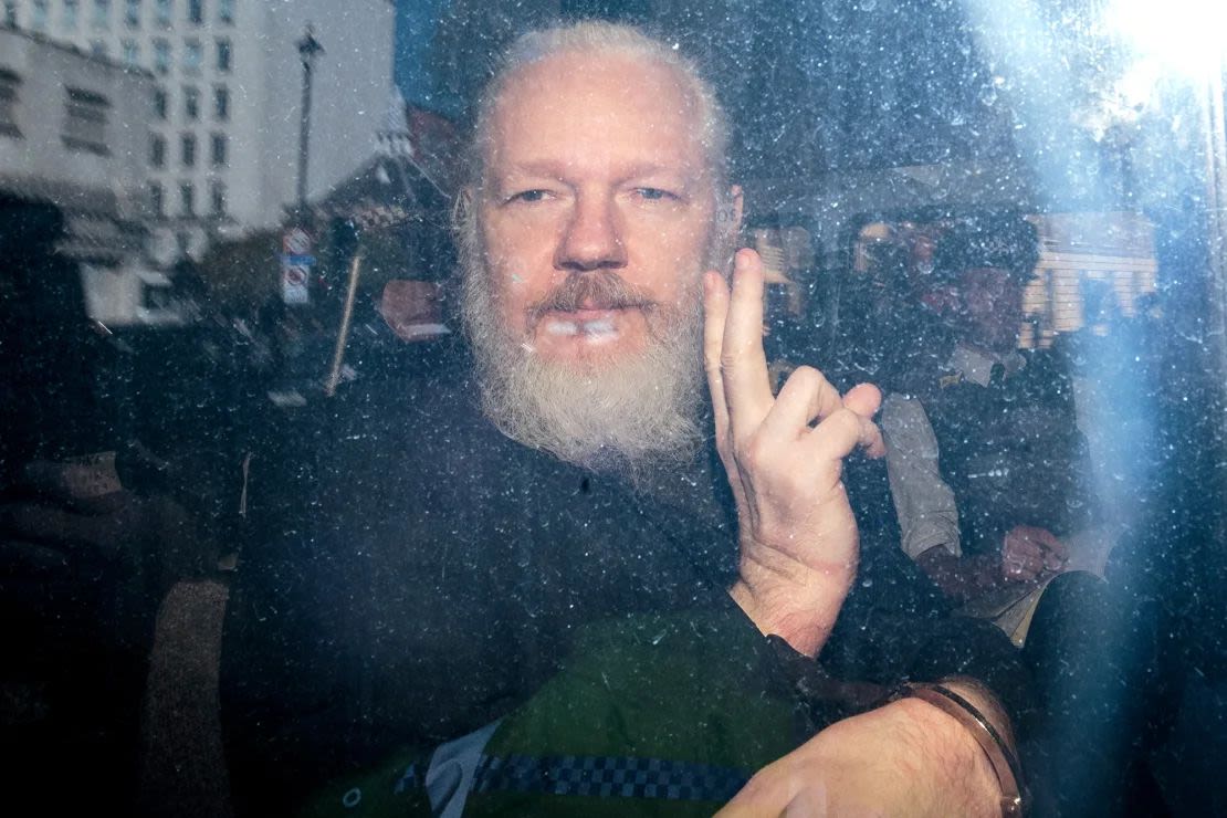 Julian Assange gestures to the media from a police vehicle upon arrival at Westminster Magistrates' Court on April 11, 2019 in London, England.