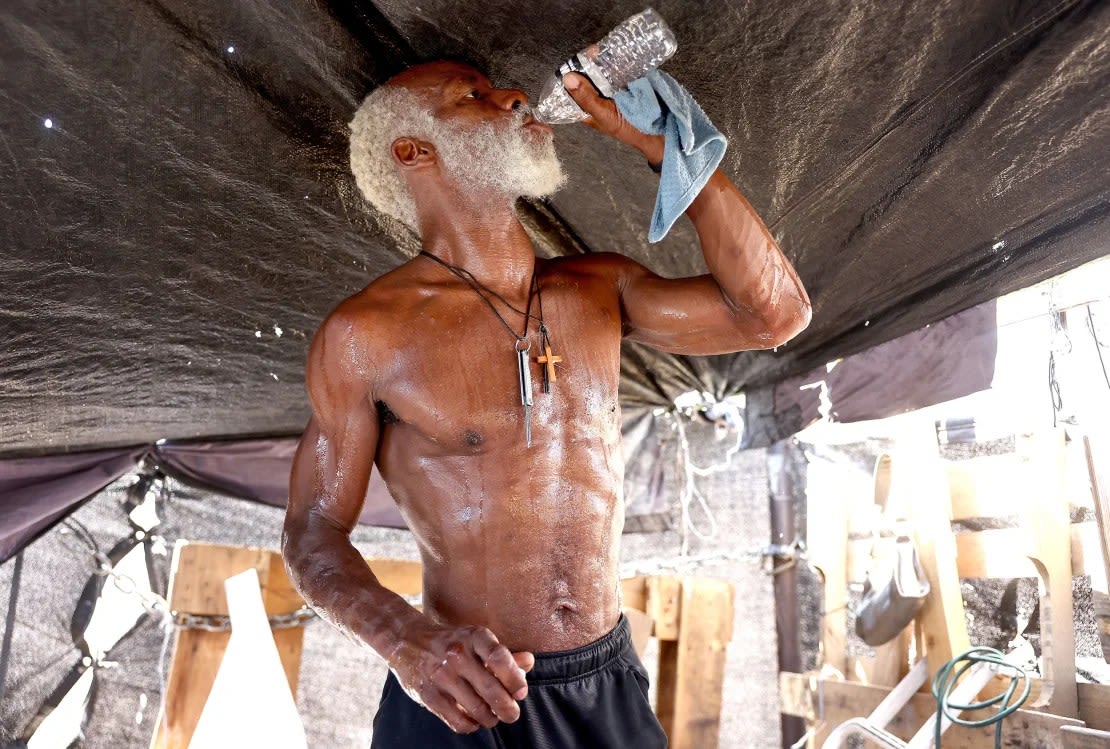 Un hombre bebe agua en su tienda de campaña en "la Zona", el mayor campamento de personas sin hogar de Phoenix, Arizona, durante la peor ola de calor registrada en la ciudad, el 25 de julio de 2023.