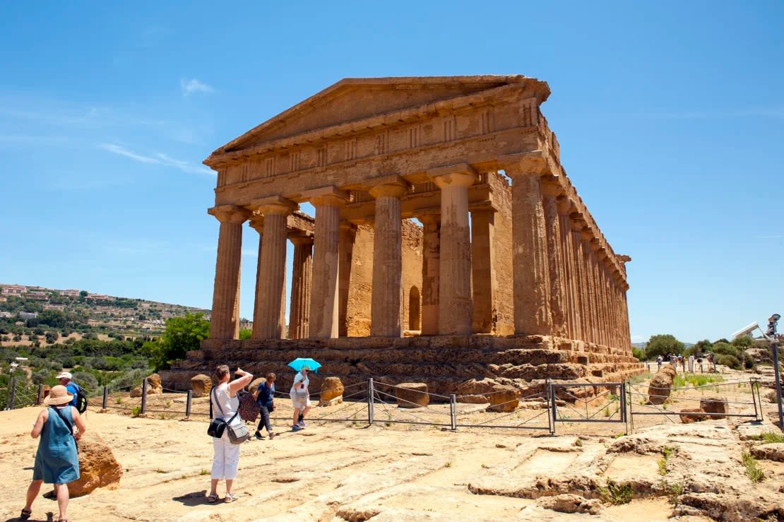 Turistas en el Templo de la Concordia, un antiguo yacimiento arqueológico griego a las afueras de Agrigento, en el sur de Sicilia, Italia.