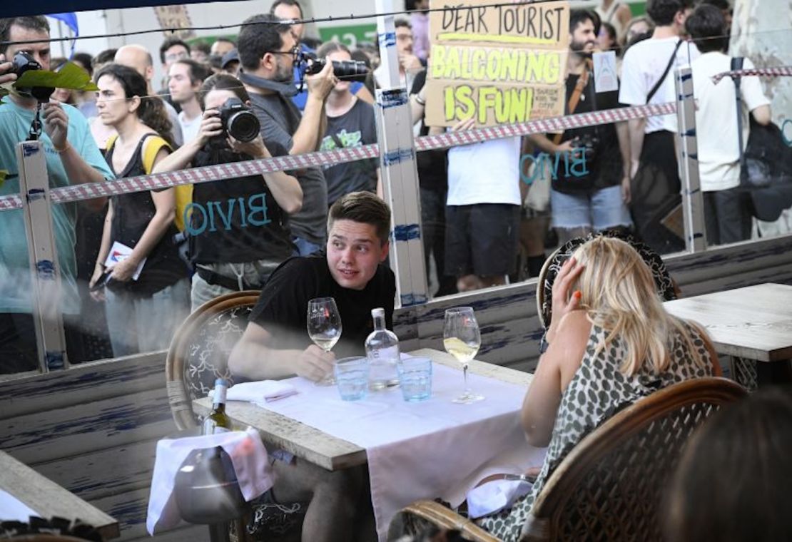 Comensales se agachan mientras los manifestantes desfilan frente a un restaurante el 6 de julio de 2024.