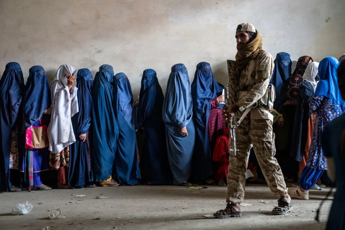 Un combatiente talibán monta guardia mientras las mujeres esperan para recibir raciones de comida distribuidas por un grupo de ayuda humanitaria, en Kabul, Afganistán, el 23 de mayo de 2023.