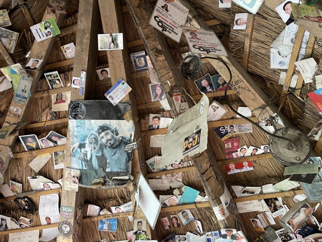 Fotos, tarjetas de identificación y otros recuerdos dejados por los visitantes en el techo de paja de la cabaña donde las sobrinas nietas (y aprendices) de Whang-Od tatúan. Crédito: Girlie Linao/picture alliance/Getty Images