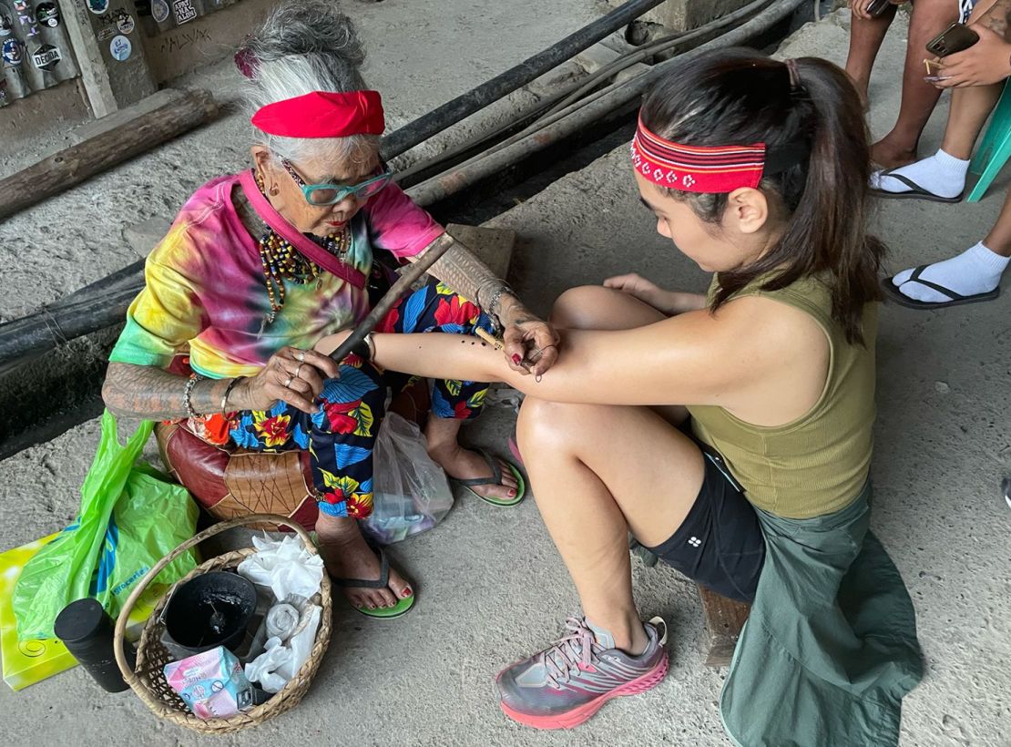 Whang-Od utiliza una espina de pomelo manchada de tizne como aguja de tatuaje y la golpea repetidamente para crear su característica marca de tres puntos. Crédito: Kathleen Magramo/CNN