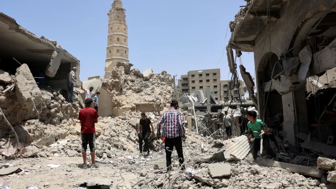 Los rescatistas se encuentran sobre los escombros de los edificios destruidos tras el bombardeo israelí cerca de la Gran Mezquita Omari en la Ciudad Vieja de la ciudad de Gaza. Crédito: Omar Al-Qattaa/AFP/Getty Images.