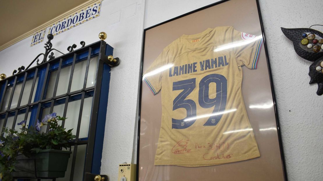 En el bar El Cordobés atesoran esta camiseta de Lamine Yamal con el número 39, regalo del padre del futbolista. El dueño dice que desde pequeño se notaban las condiciones de Lamine, aunque no se podía saber hasta dónde llegaría tan rápido.