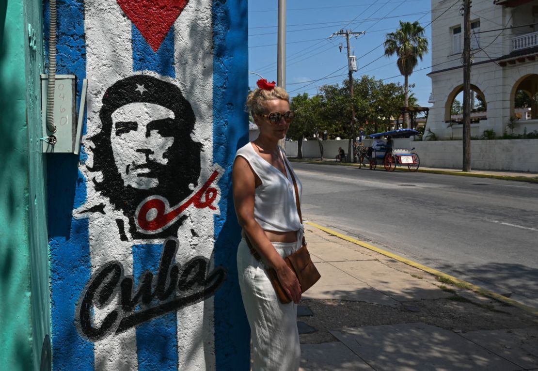 Un turista posa para una fotografía junto a una pared con un graffiti que representa al fallecido líder cubano-argentino Ernesto Che Guevara, en Varadero, provincia de Matanzas, Cuba, el 5 de abril de 2024.