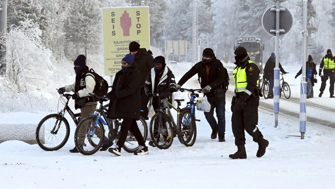 Guardias fronterizos finlandeses y migrantes con bicicletas en el paso fronterizo internacional de Salla, en la Laponia finlandesa, el 21 de noviembre de 2023.