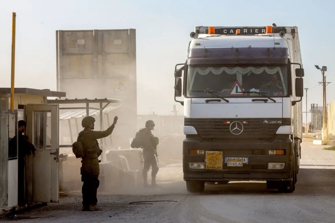 Soldados israelíes hacen guardia mientras camiones que transportan ayuda humanitaria avanzan en el lado israelí del cruce fronterizo de Kerem Shalom el 19 de diciembre de 2023. Crédito: Menahem Kahana/AFP/Getty Images.